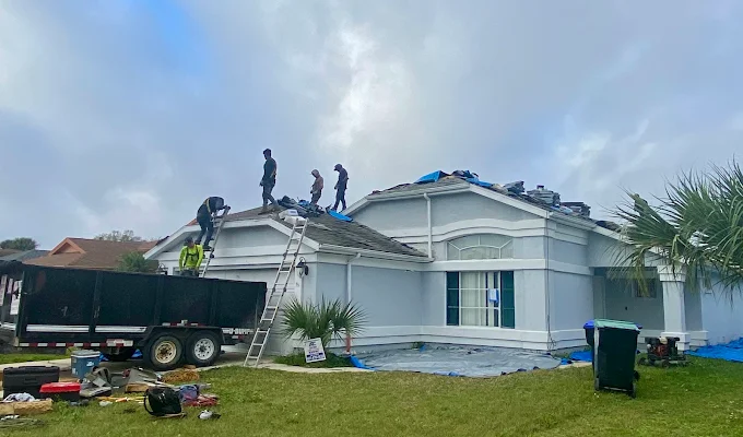 Expert Affordable Roofing crew tearing off an old roof, dump trailer in the driveway